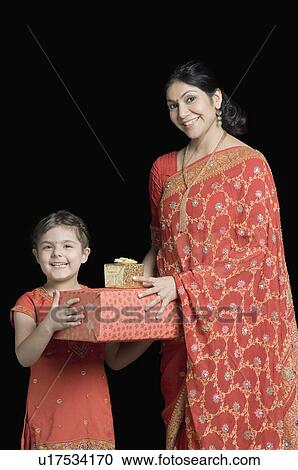 Stock Image - Portrait of a mid adult woman giving gifts to her daughter. Fotosearch