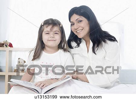 Portrait of a mid adult woman sitting with her daughter on the bed and smiling View Large Photo Image Stock Photo - Portrait of a mid adult woman sitting with her daughter on the bed and smiling. Fotosearch