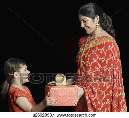 Stock Photo - Side profile of a mid adult woman giving gifts to her daughter. Fotosearch