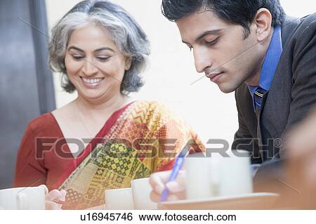 Businessman and a businesswoman working in a conference room View Large Photo Image Stock Photograph - Businessman and a businesswoman working in a conference room. Fotosearch