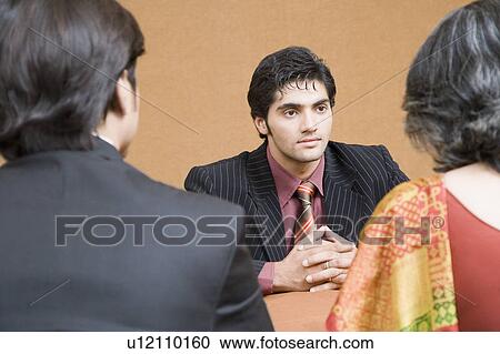 Businessman discussing with two business executives in a meeting View Large Photo Image Stock Image - Businessman discussing with two business executives in a meeting. Fotosearch