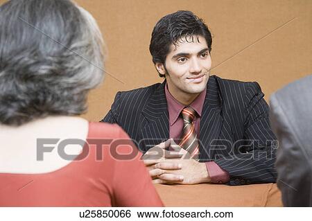 Businessman discussing with two business executives in a meeting View Large Photo Image Stock Photograph - Businessman discussing with two business executives in a meeting. Fotosearch