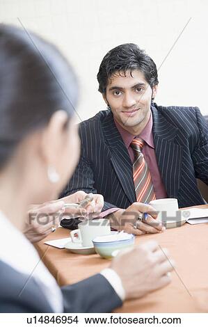 Picture - Businesswoman and a businessman discussing in a conference room. Fotosearch