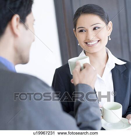 Close-up of a businessman and a businesswoman holding cups of tea View Large Photo Image Stock Image - Close-up of a businessman and a businesswoman holding cups of tea. Fotosearch