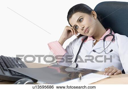Close-up of a female doctor thinking in an office View Large Photo Image Stock Photograph - Close-up of a female doctor thinking in an office. Fotosearch
