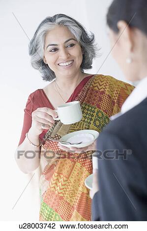 Close-up of two businesswomen holding cups of tea View Large Photo Image Stock Image - Close-up of two businesswomen holding cups of tea. Fotosearch