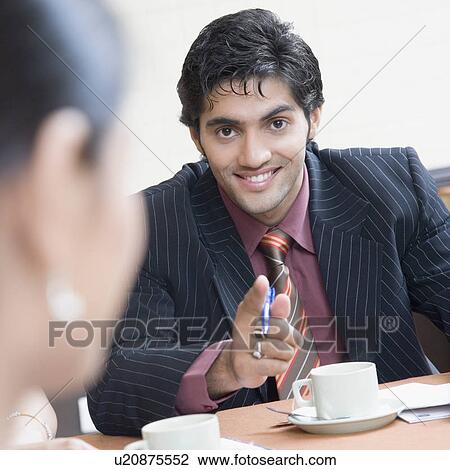 Stock Image - Portrait of a businessman pointing forward and smiling. Fotosearch