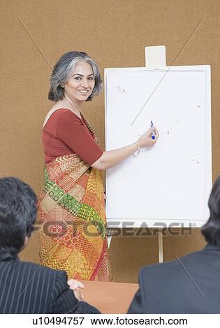 Stock Photo - Portrait of a businesswoman giving presentation in a meeting and smiling. Fotosearch