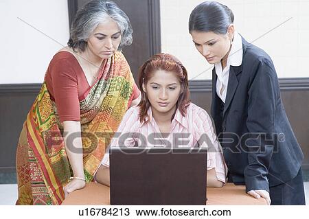 Three businesswomen using a laptop View Large Photo Image Stock Image - Three businesswomen using a laptop. Fotosearch
