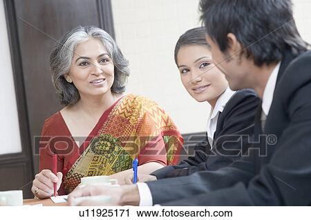 Two businesswomen and a businessman discussing in a conference room View Large Photo Image Stock Image - Two businesswomen and a businessman discussing in a conference room. Fotosearch