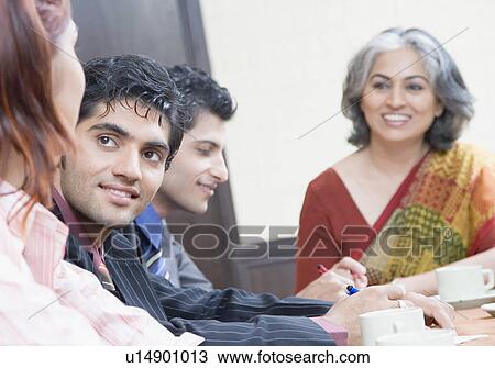 Stock Image - Two businesswomen and two businessmen discussing in a conference room. Fotosearch