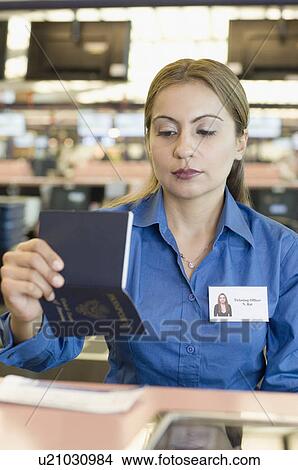 Airline check-in attendant looking at a passport View Large Photo Image Picture - Airline check-in attendant looking at a passport. Fotosearch