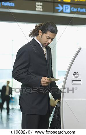 Businessman using express check-in service at an airport View Large Photo Image Stock Photo - Businessman using express check-in service at an airport. Fotosearch