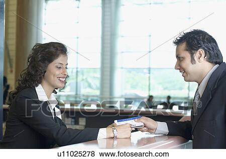 Businessman with an airline check-in attendant at an airport check-in counter View Large Photo Image Stock Photo - Businessman with an airline check-in attendant at an airport check-in counter. Fotosearch