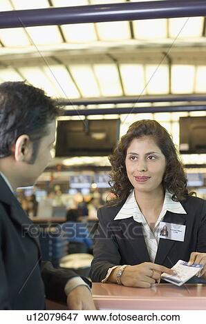 Stock Photo - Businessman with an airline check-in attendant at an airport check-in counter. Fotosearch