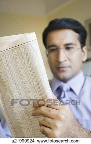 Close-up of a businessman reading a newspaper View Large Photo Image Picture - Close-up of a businessman reading a newspaper. Fotosearch