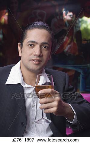 Portrait of a mid adult man sitting in a restaurant and holding a glass of wine View Large Photo Image Stock Photo - Portrait of a mid adult man sitting in a restaurant and holding a glass of wine. Fotosearch