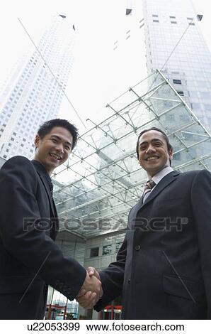 Portrait of two businessmen shaking hands and smiling, Singapore View Large Photo Image Stock Photo - Portrait of two businessmen shaking hands and smiling, Singapore. Fotosearch