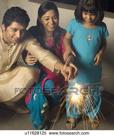 Close-up of a couple holding a sparkler with their daughter and smiling View Large Photo Image Stock Photography - Close-up of a couple holding a sparkler with their daughter and smiling. Fotosearch