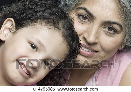 Close-up of a mature woman smiling with her granddaughter View Large Photo Image Stock Photography - Close-up of a mature woman smiling with her granddaughter. Fotosearch