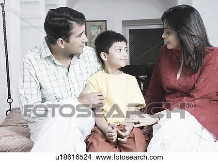 Close-up of a mid adult couple with their son sitting on a porch swing View Large Photo Image Picture - Close-up of a mid adult couple with their son sitting on a porch swing. Fotosearch
