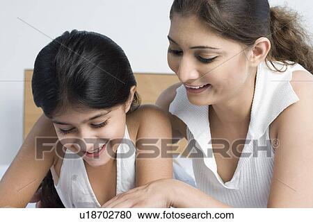 Close-up of a young woman smiling with her daughter View Large Photo Image Stock Image - Close-up of a young woman smiling with her daughter. Fotosearch