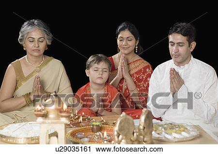 Family praying in front of figurines of God View Large Photo Image Stock Image - Family praying in front of figurines of God. Fotosearch