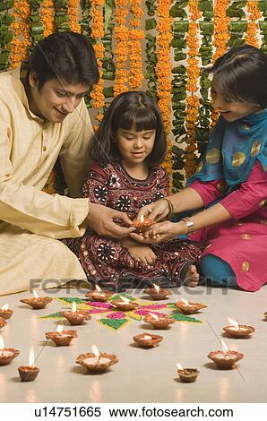 Girl with her parents lighting oil lamps View Large Photo Image Stock Photography - Girl with her parents lighting oil lamps. Fotosearch