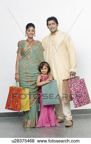 Mid adult man and a young woman with their daughter standing with shopping bags View Large Photo Image Stock Photo - Mid adult man and a young woman with their daughter standing with shopping bags. Fotosearch