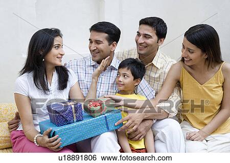 Mid adult woman holding gifts and sitting with her family View Large Photo Image Stock Photograph - Mid adult woman holding gifts and sitting with her family. Fotosearch