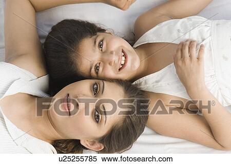 Stock Photography - Portrait of a girl lying on the bed with her mother and smiling. Fotosearch