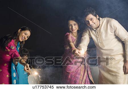 Stock Photography - Portrait of a mid adult man with two young women and a girl celebrating a diwali festival. Fotosearch