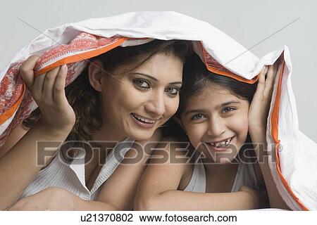 Portrait of a young woman lying with her daughter under a blanket and smiling View Large Photo Image Stock Image - Portrait of a young woman lying with her daughter under a blanket and smiling. Fotosearch