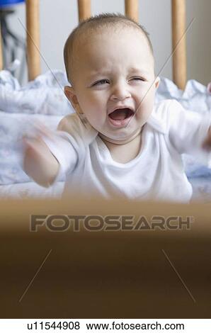 Stock Photo - Baby boy crying in a crib. Fotosearch