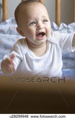 Stock Photo - Baby boy crying in a crib. Fotosearch