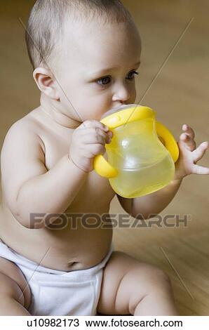 Stock Image - Close-up of a baby boy drinking water from a water bottle. Fotosearch