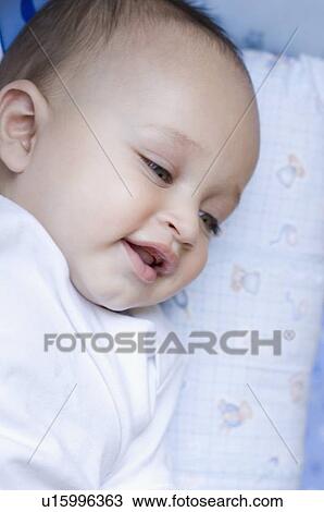 Stock Image - Close-up of a baby boy lying down and smiling. Fotosearch