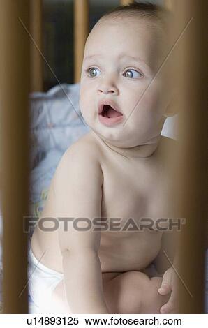 Close-up of a baby boy sitting in a crib and looking away View Large Photo Image Stock Photography - Close-up of a baby boy sitting in a crib and looking away. Fotosearch