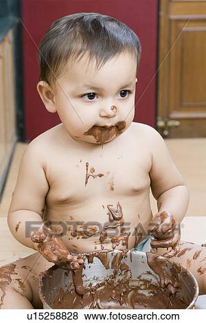 Stock Photo - Close-up of a baby girl eating chocolate sauce. Fotosearch