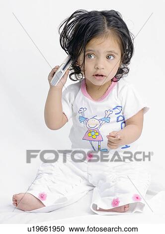 Stock Image - Close-up of a baby girl holding a mobile phone. Fotosearch