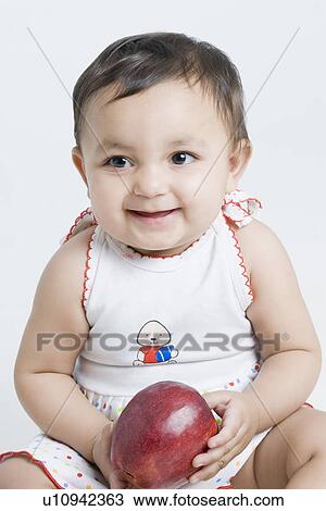 Close-up of a baby girl smiling and holding an apple View Large Photo Image Stock Image - Close-up of a baby girl smiling and holding an apple. Fotosearch