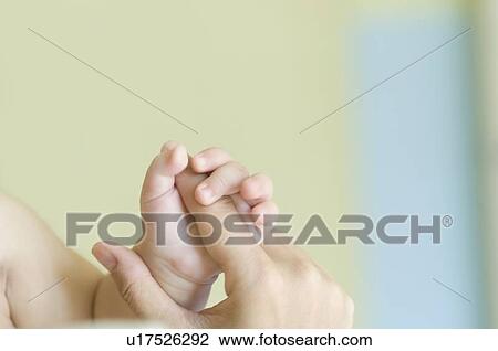 Stock Image - Close-up of a baby's hand holding a person's finger. Fotosearch