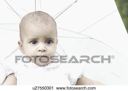 Stock Image - Close-up of a girl with an umbrella behind her. Fotosearch