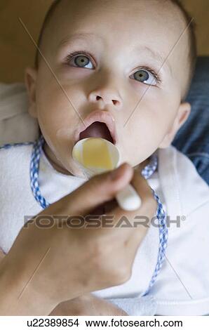 Close-up of a person's hand feeding food to a baby boy View Large Photo Image Picture - Close-up of a person's hand feeding food to a baby boy. Fotosearch