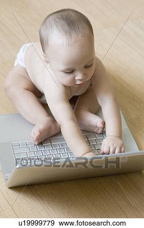 Stock Photo - High angle view of a baby boy playing with a laptop. Fotosearch