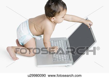 High angle view of a baby girl playing with a laptop View Large Photo Image Stock Image - High angle view of a baby girl playing with a laptop. Fotosearch