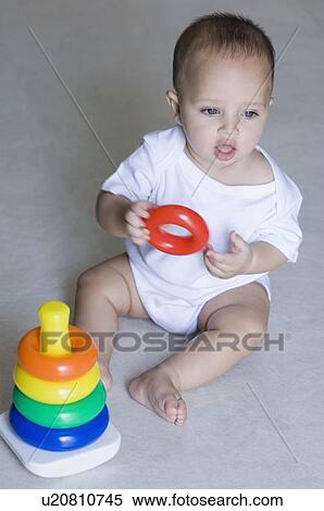 Stock Photography - High angle view of a baby sitting and playing with stacking ring. Fotosearch