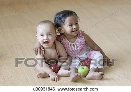 High angle view of a girl sitting with her arm around a baby boy and smiling View Large Photo Image Stock Photograph - High angle view of a girl sitting with her arm around a baby boy and smiling. Fotosearch