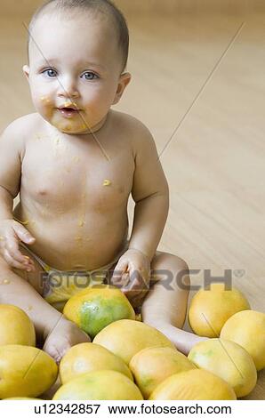 Portrait of a baby sitting on the hardwood floor and getting messy with mangoes View Large Photo Image Stock Photo - Portrait of a baby sitting on the hardwood floor and getting messy with mangoes. Fotosearch