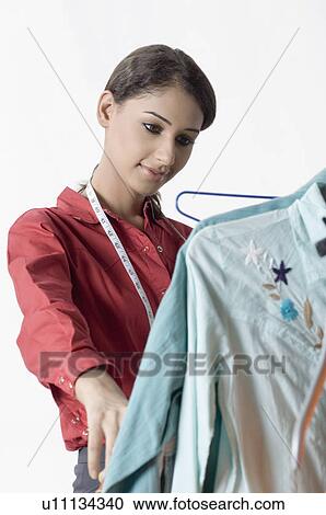 Stock Image - Close-up of a female fashion designer looking at designers clothes. Fotosearch